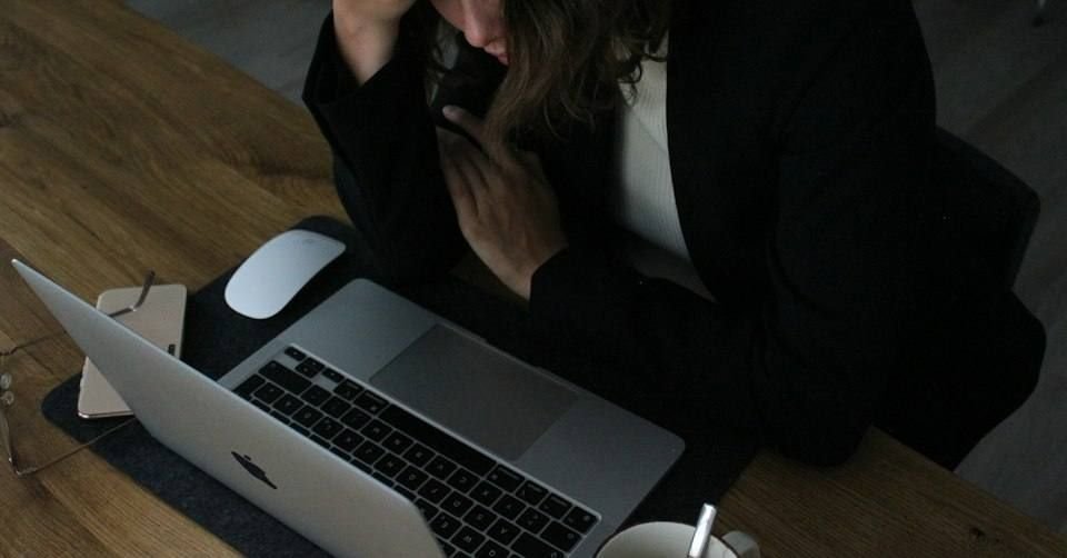 A stressed business owner with her head in her hands at a laptop