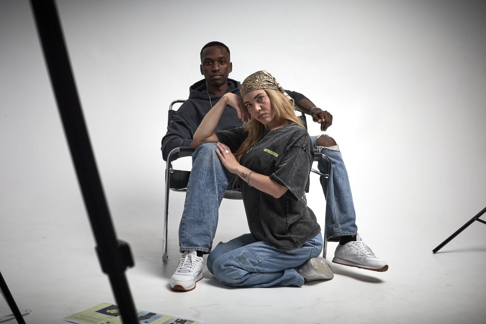 Two models posed around a folding chair in the studio
