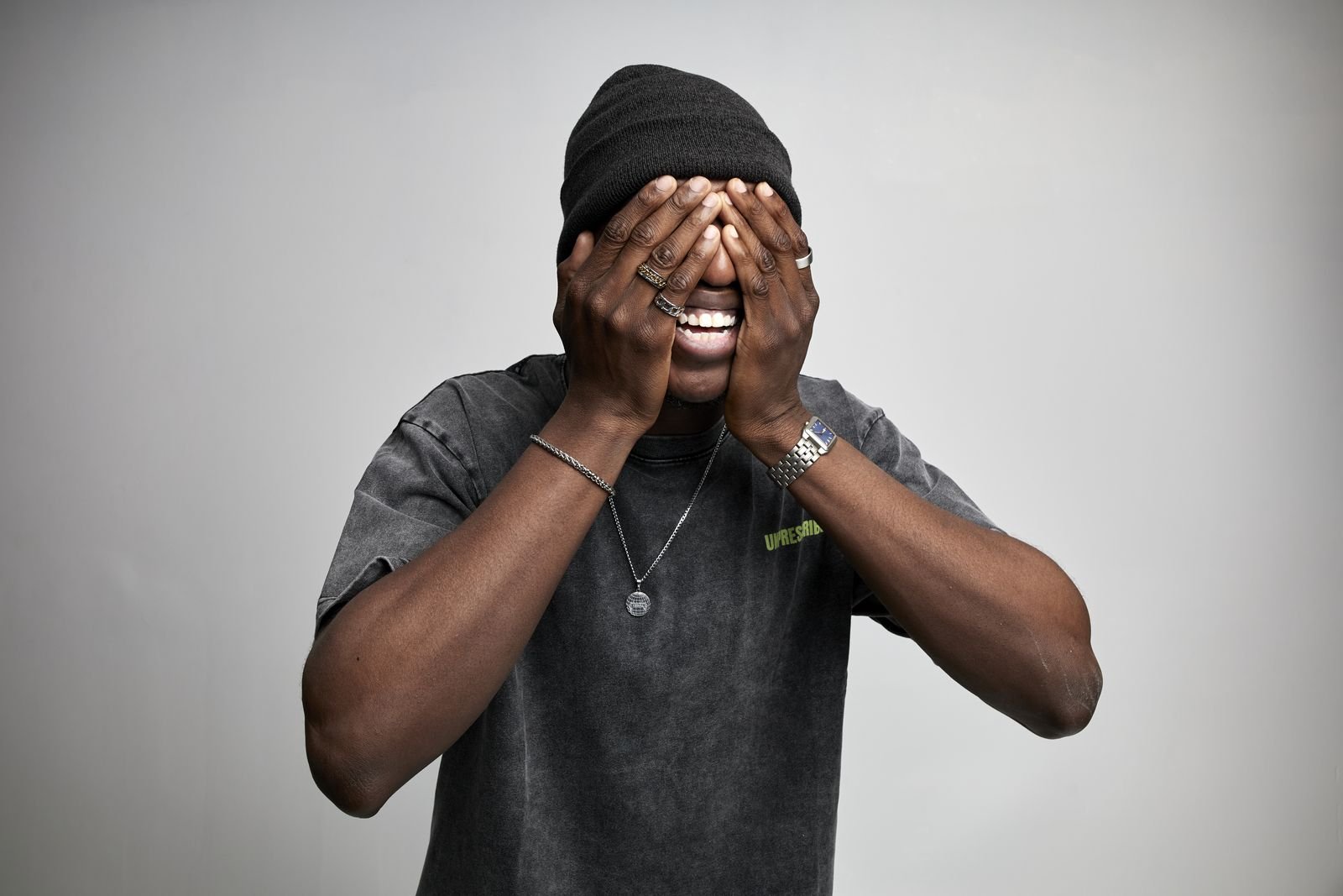 Model covering his eyes and grinning in an Unprescribed tee