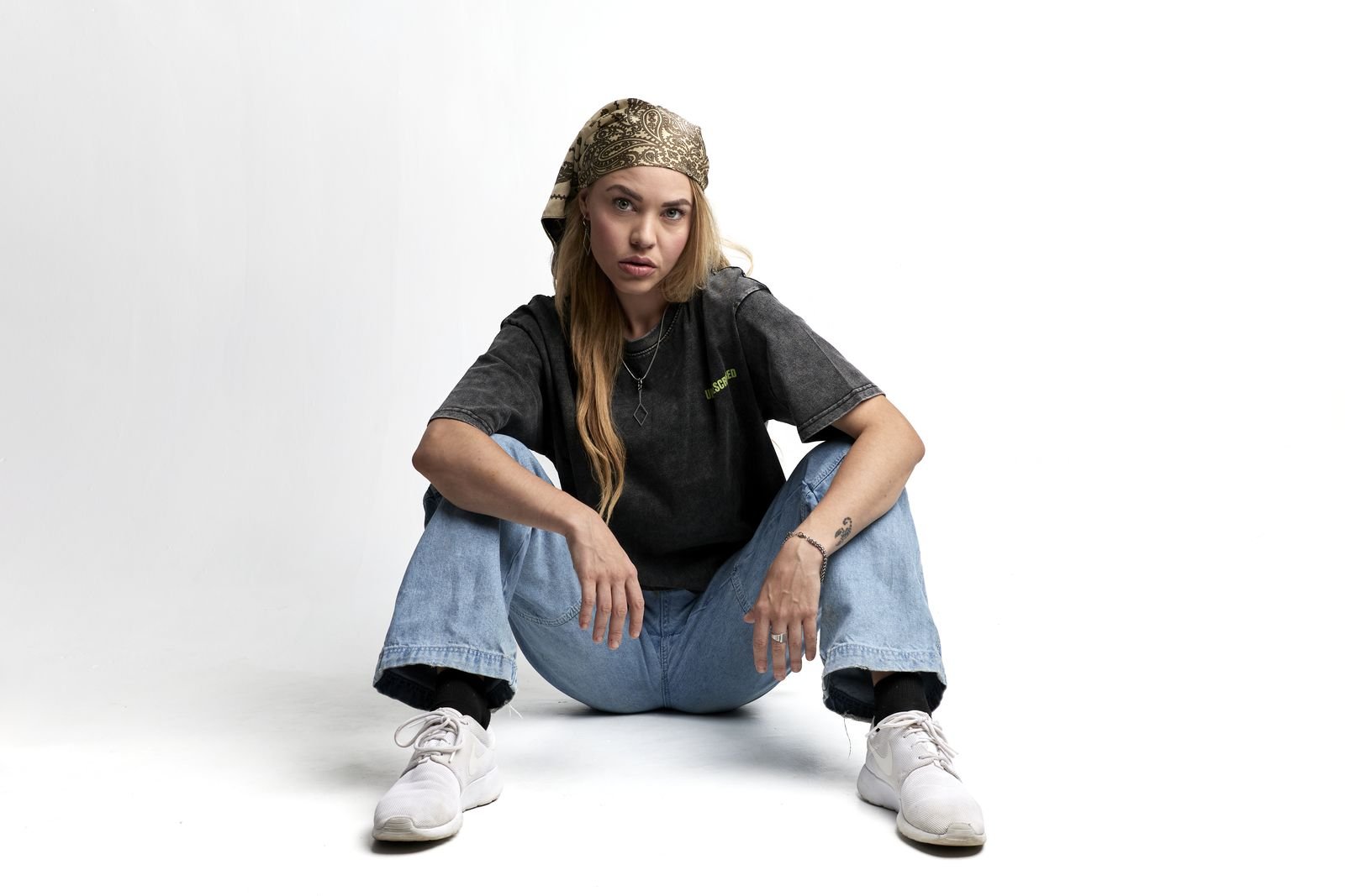 Model sitting cross-legged on the studio floor in an Unprescribed tee