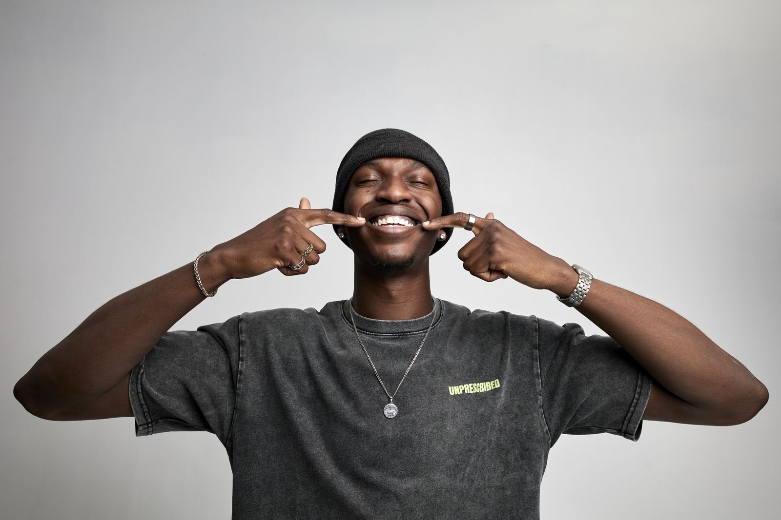 Model pushing a smile with his fingers in an Unprescribed tee
